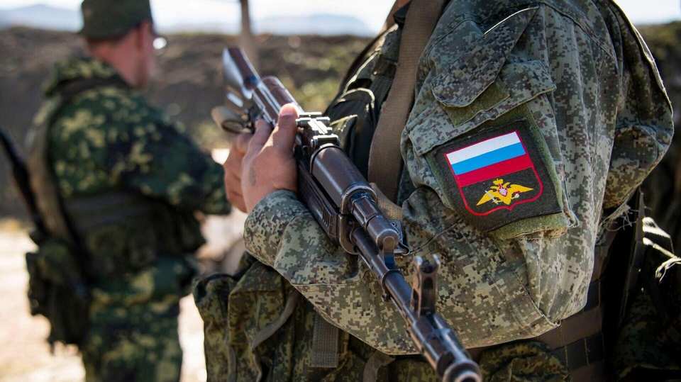 Контрактник с автоматом и шевроном с флагом России на рукаве